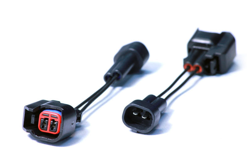 Injector Dynamics USCAR to Denso PnP adapter pair, black connectors with red locks, angled view