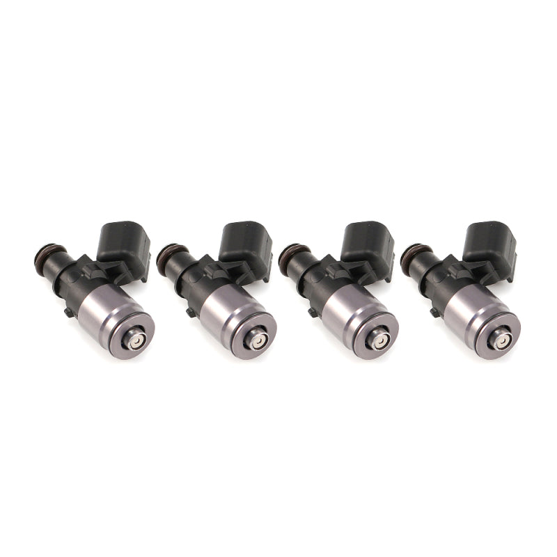 Set of four Injector Dynamics ID1050 injectors for Subaru BRZ/FA20 2.0L, angled view showing machined tops and WRX-16B bottom adaptors with electrical