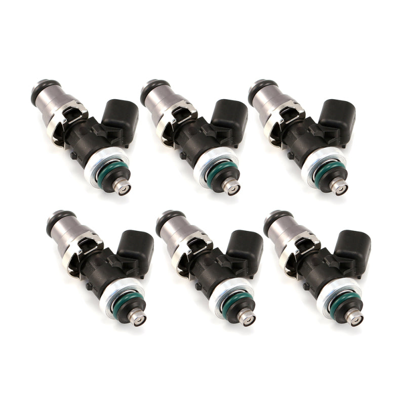 Set of six Injector Dynamics 1050 XDS fuel injectors, angled view showing 14mm adaptor tops and GTR lower spacers with green O-rings.