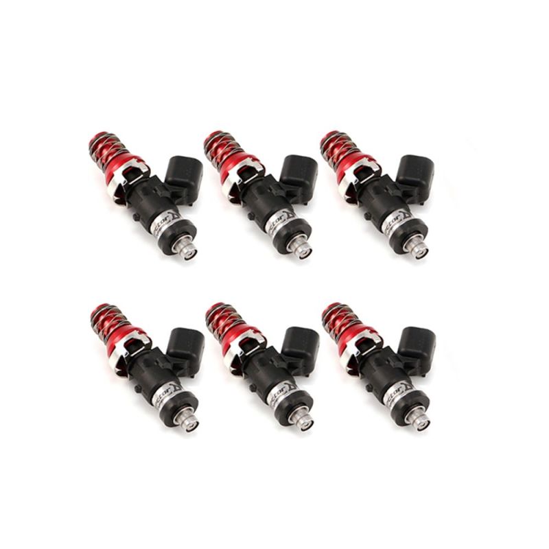 Set of six ID1050X fuel injectors, angled view showing red top hats, black bodies and lower Denso connectors.