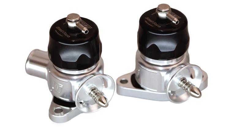 Two Turbosmart Nissan GTR R35 Dual Port Smart Port BOVs with black caps, side by side, showing silver mounting flanges and hose fittings.