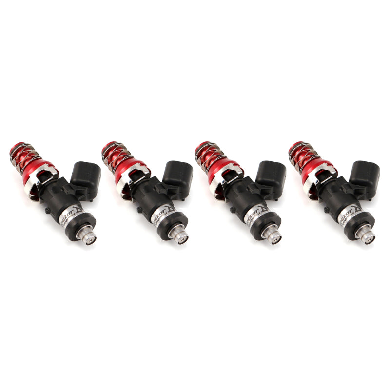 Set of four ID1050X fuel injectors, angled view showing red top adapters, coils and electrical connectors.