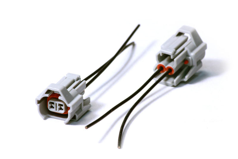 Injector Dynamics Denso female connector pigtail kit, two gray plugs with wire leads on white background