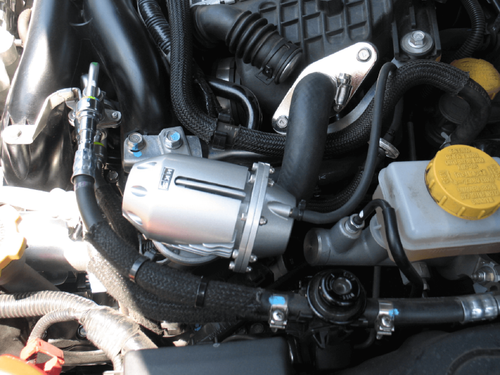 HKS SSQV4 BOV silver valve installed in engine bay, close up with hoses and brake reservoir visible