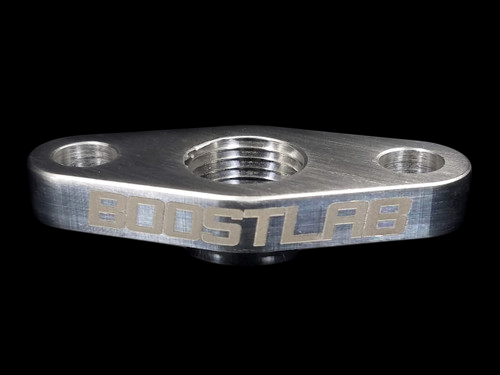 Boost Lab billet T3/T4 turbo oil drain flange, angled view showing threaded 1/2 NPT center port and two bolt holes