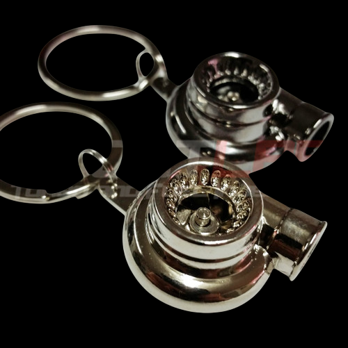 Two chrome Boost Lab turbo key chains with spinning wheels, keyrings attached, on black background